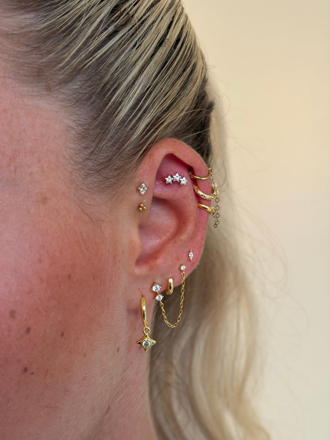 Full ear stack with multiple earrings styled alongside a sleek slick back hairstyle.