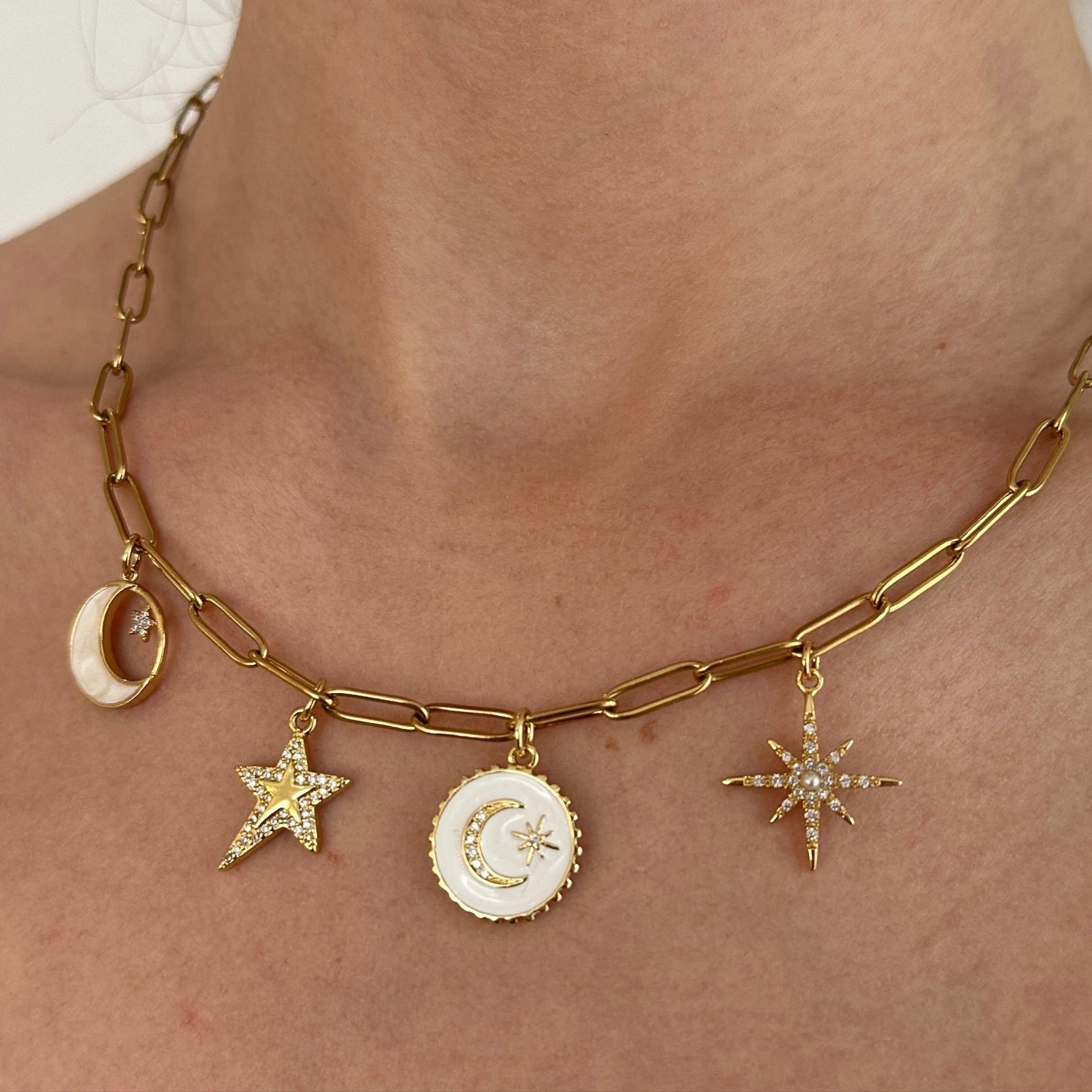 Gold necklace with star and moon charms on a person's neck