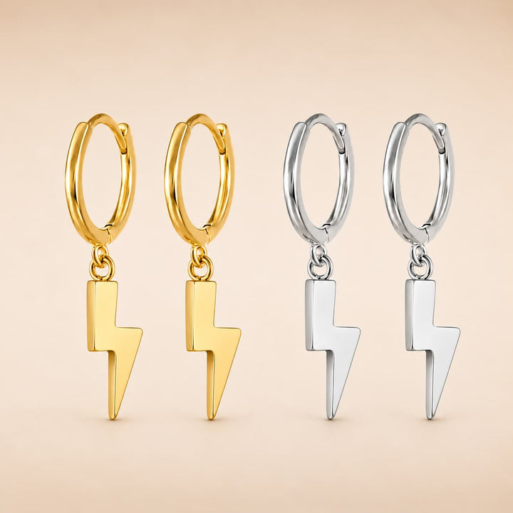 Four small hoop earrings with dangling lightning bolt charms, shown in two metal finishes: gold on the left and silver on the right, against a soft beige background.