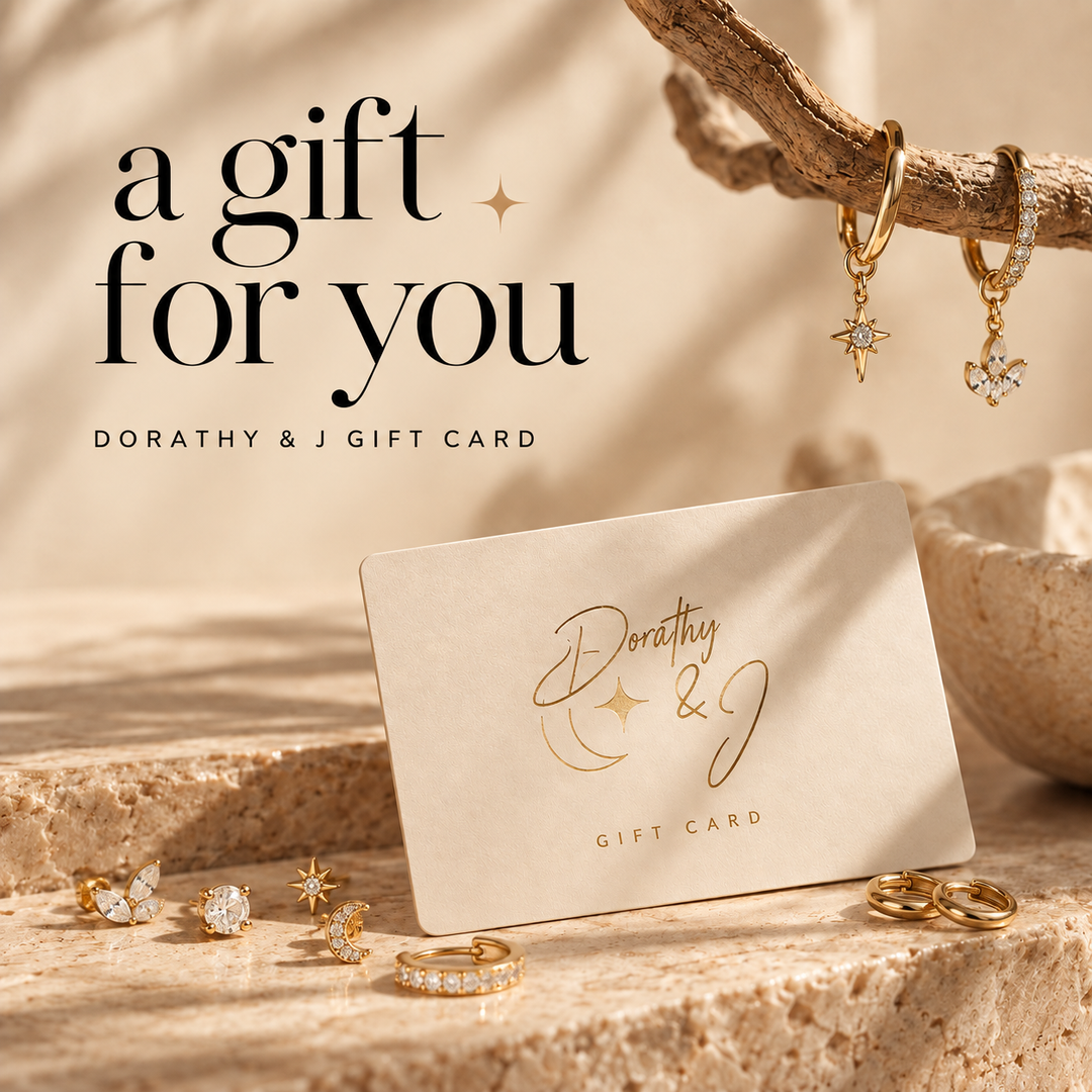 A Dorothy &amp; J gift card styled on a stone surface with gold jewelry nearby, under the text &