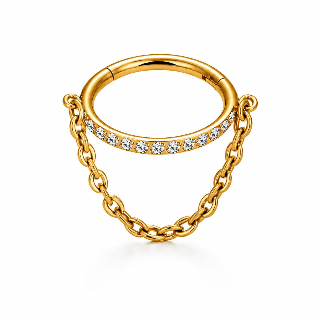 A gold ring with a curved band featuring a row of clear stones and a dangling chain link design, shown on a clean white background.
