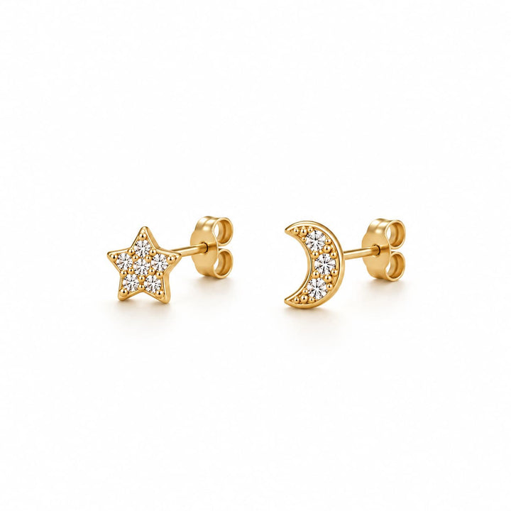 A pair of gold stud earrings, one shaped like a five-pointed star and the other like a crescent moon, both adorned with small clear pavé stones, shown on a clean white background.