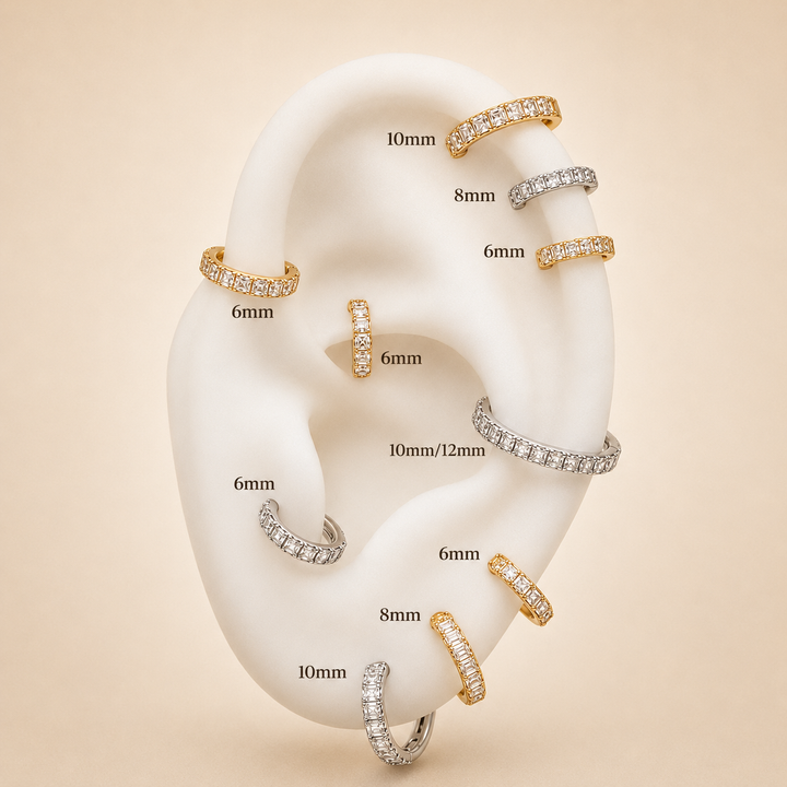 A white ear-shaped display form holding multiple small hoop and ring earrings on a beige background. Black text labels each piece with sizes such as 6mm, 8mm, 10mm, and 10mm/12mm.