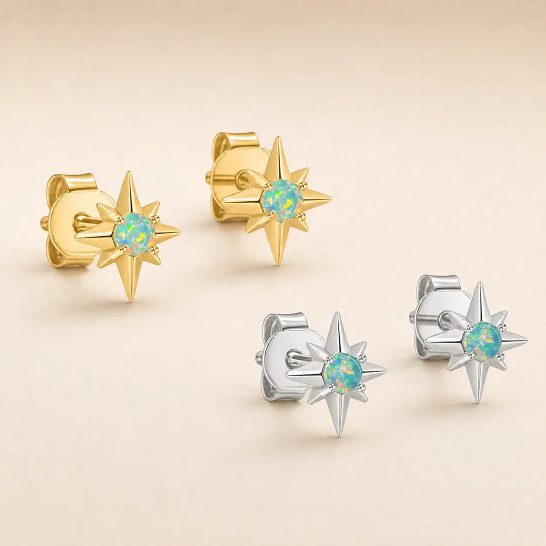 Four star-shaped stud earrings with round iridescent opal centers, shown in gold and silver metal finishes on a warm beige background.