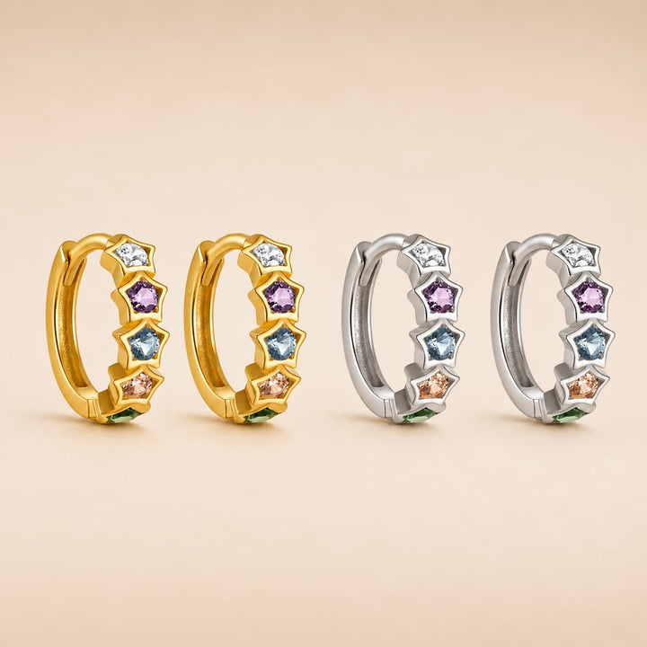 Four huggie hoop earrings arranged in two pairs on a warm beige background. Each earring features a curved gold or silver band set with star-shaped bezel settings holding small round and faceted gemstones in white, light blue, purple, pink, and green colors.