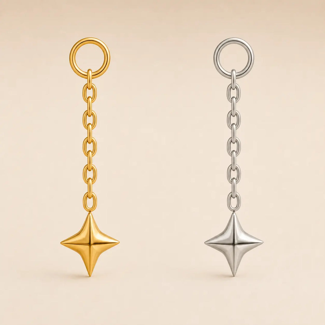 Two dangling star-shaped keychains on a warm beige background. One is gold-toned with a gold ring and chain, and the other is silver-toned with a silver ring and chain.