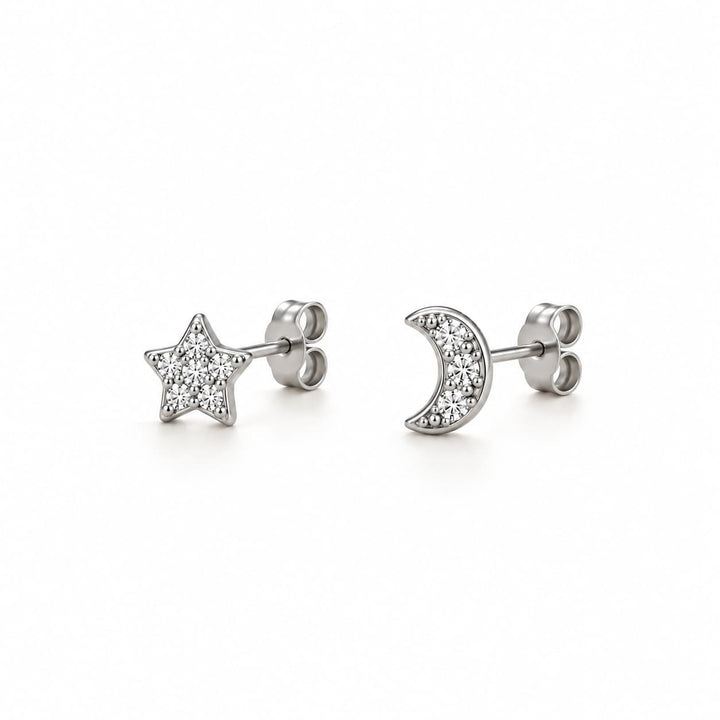 A pair of silver stud earrings, one shaped like a five-pointed star and the other like a crescent moon, both paved with small clear stones, shown on a white background.