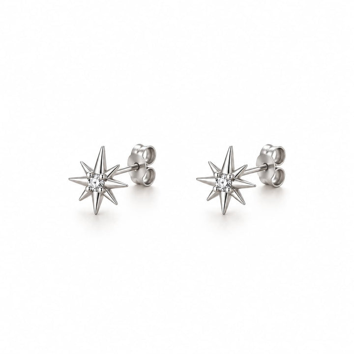A pair of silver starburst stud earrings with a single clear round-cut gemstone at the center, displayed on a clean white background.