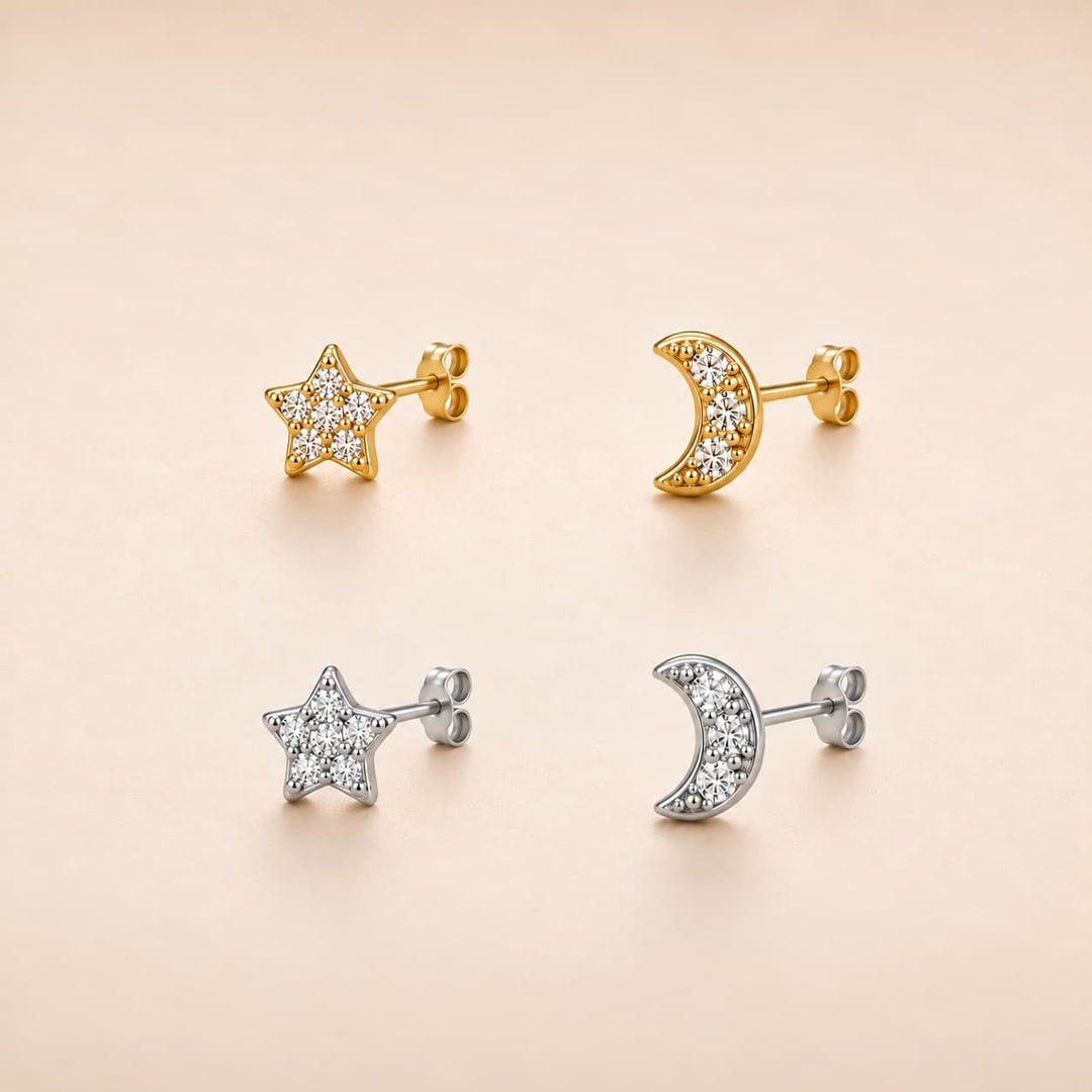 Four small stud earrings arranged in a 2x2 grid on a warm beige background: two gold-tone star and moon earrings with clear stones, and two silver-tone star and moon earrings with clear stones.